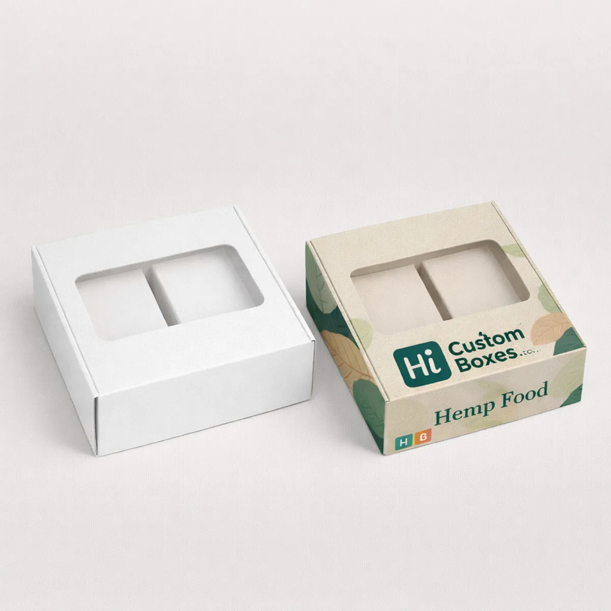 Two square boxes with clear viewing windows- including a printed version with green leaf designs and branding- class=